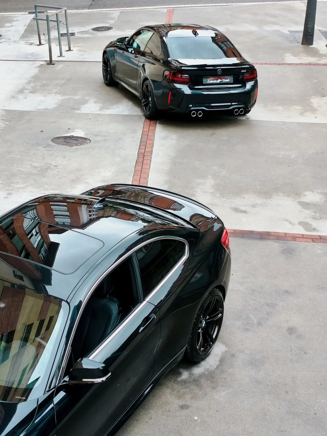 Dos BMW M2 negros vistos desde arriba con la pintura brillante tras el pulido y el detallado