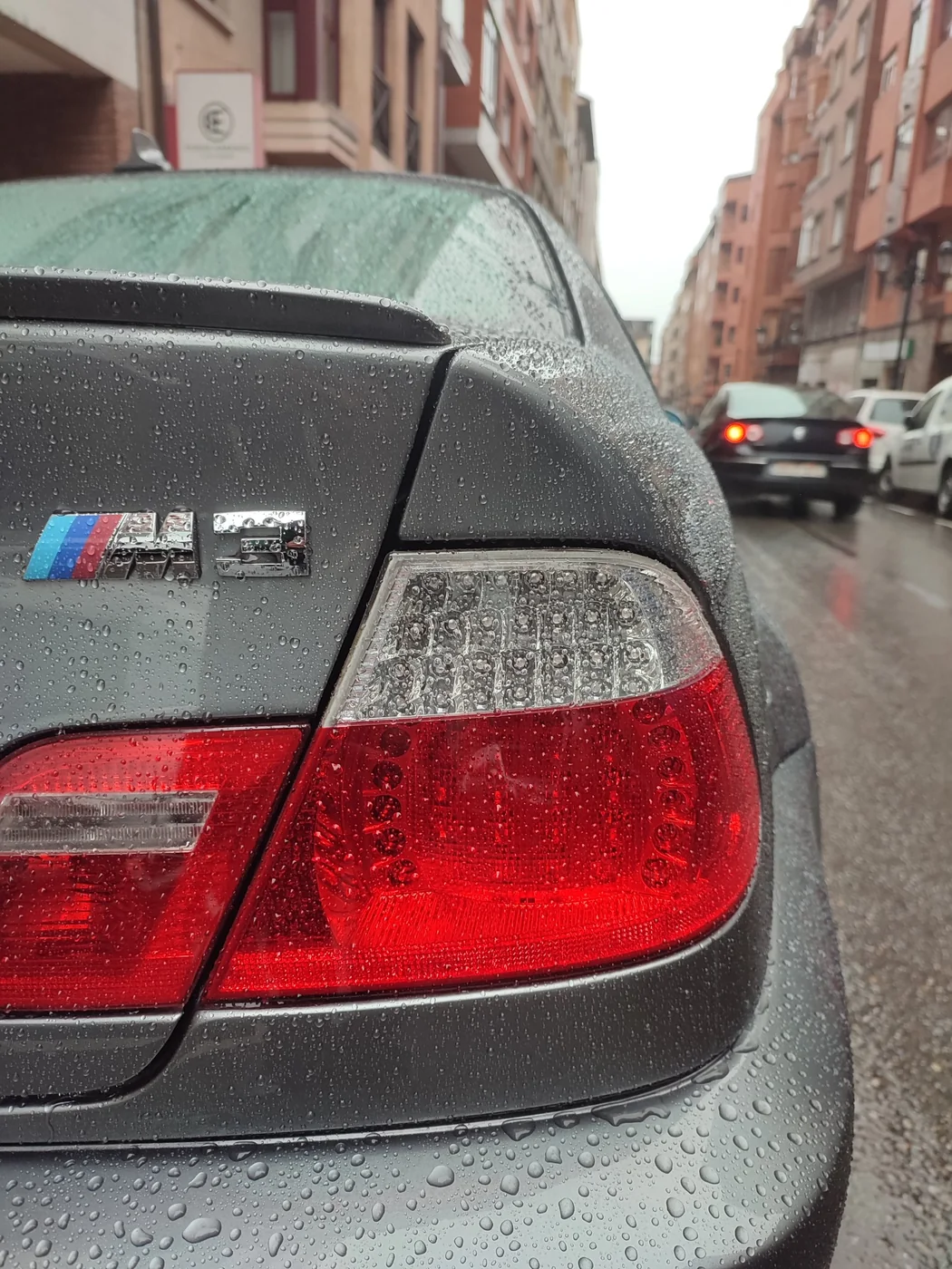 Efecto perlante de las gotas de agua sobre la pintura y los pilotos de un BMW M3 gris