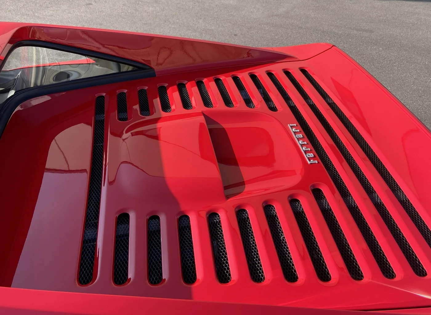 Rejillas de la tapa trasera y escudo de un Ferrari F355 rojo tras la corrección de pintura