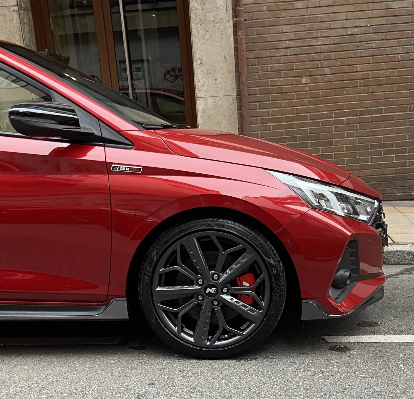 Hyundai i20 N rojo con llantas oscuras y pinza de freno roja tras detallado de carrocería y llantas