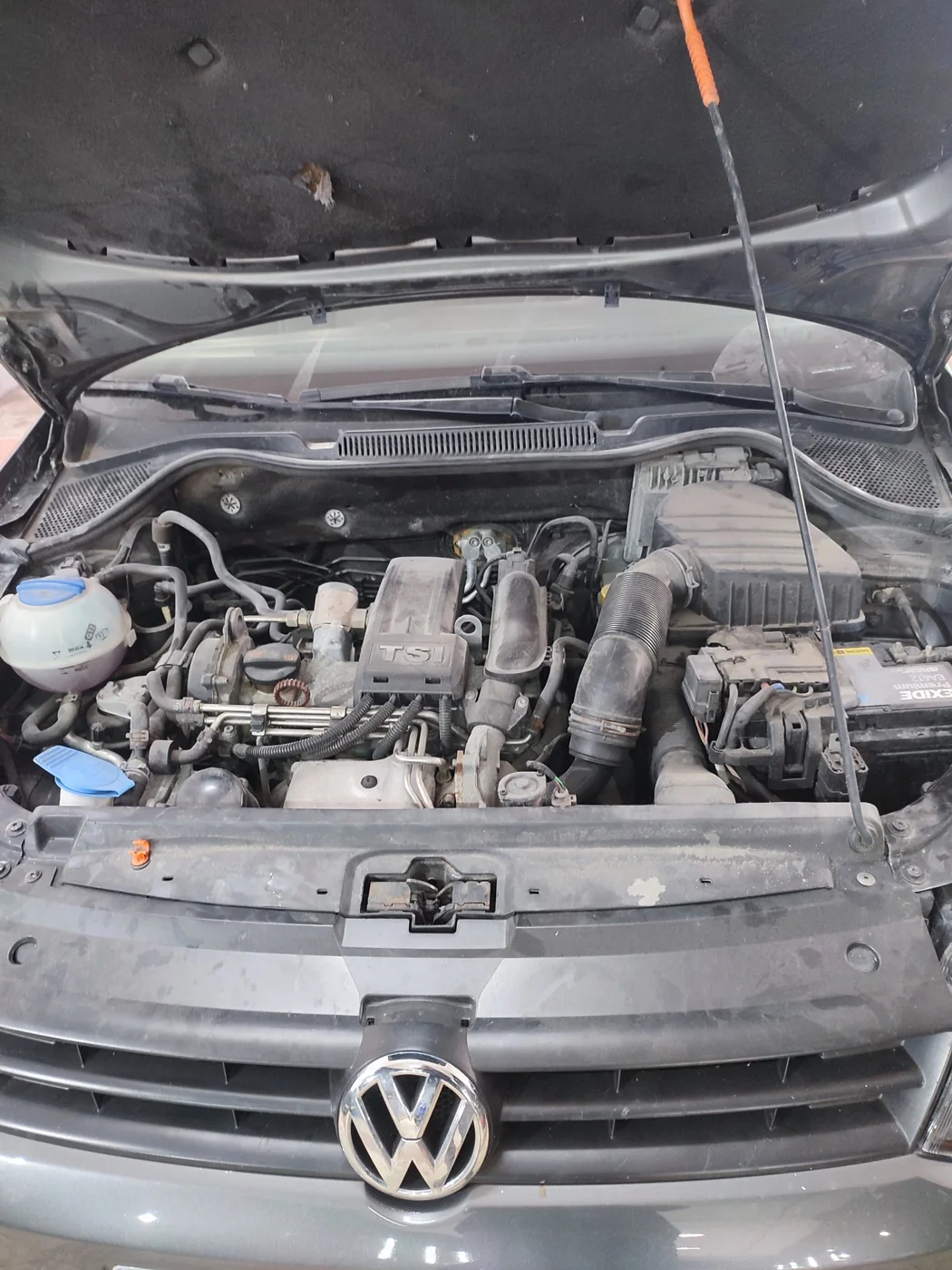 Compartimento motor sucio de un Volkswagen Polo TSI antes del detallado de motor