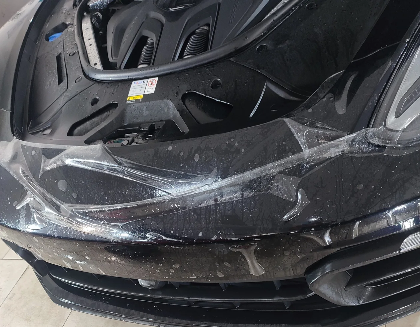 Aplicación de vinilo de protección transparente PPF en paragolpes de coche negro