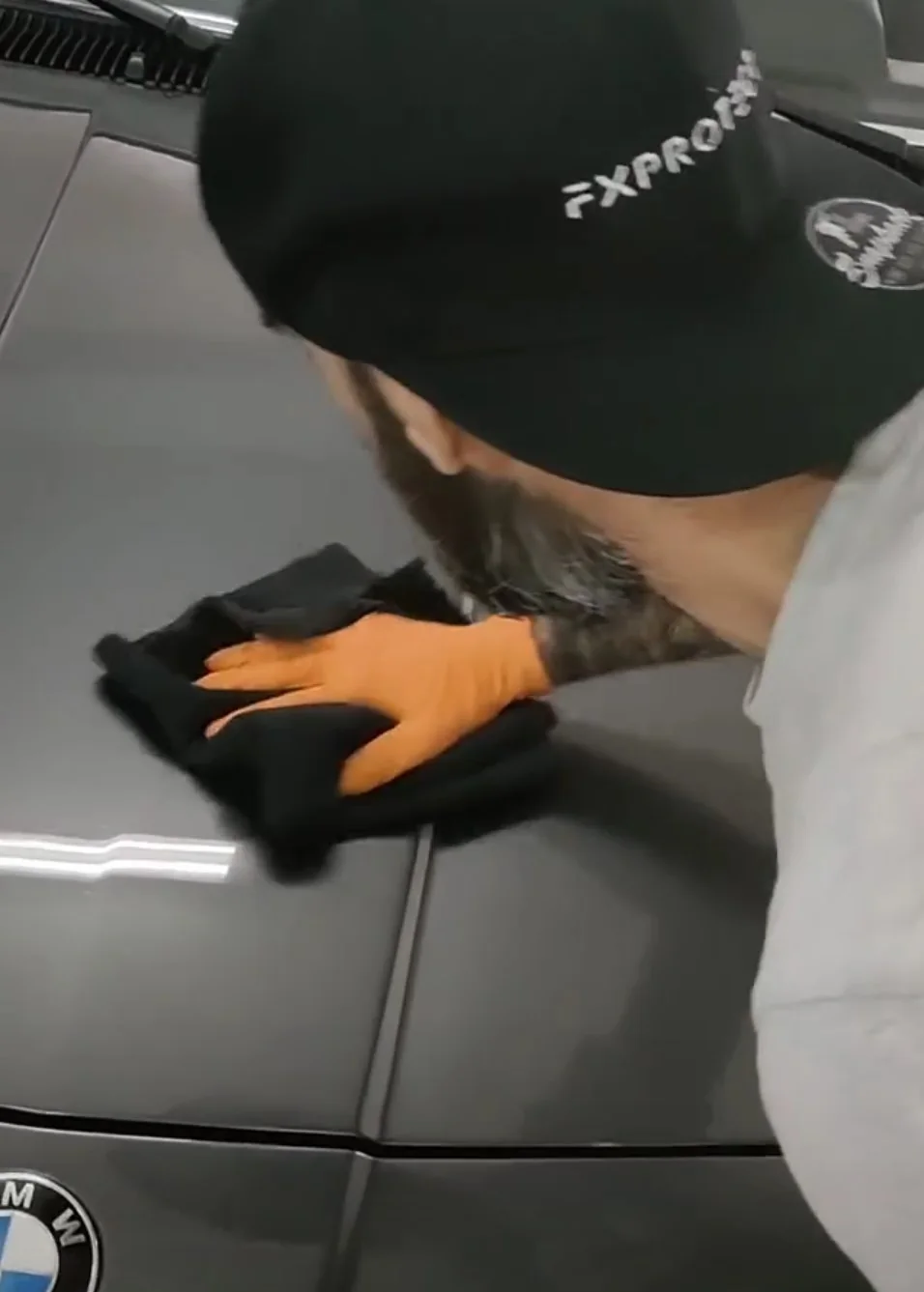 Aplicación de protección sobre el capó de un BMW gris con microfibra en el taller de Lafuente Detail