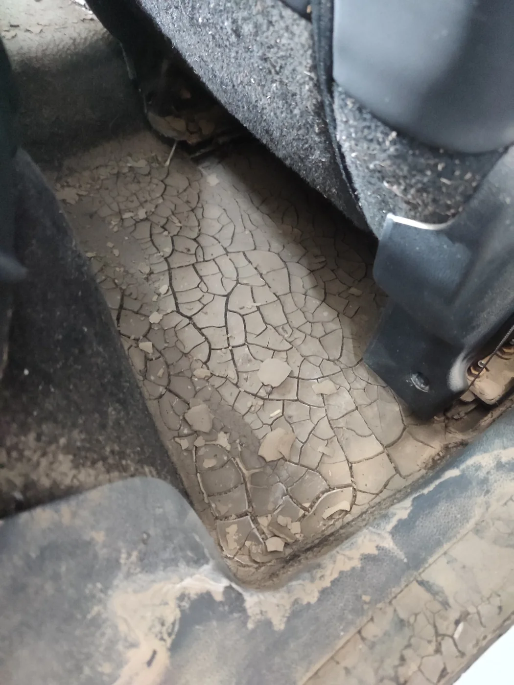 Suelo de un Renault Clio inundado con barro seco agrietado antes de la limpieza integral