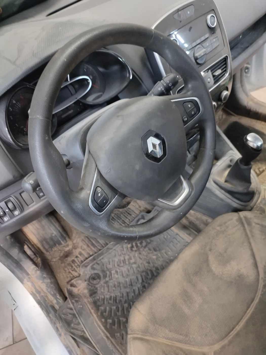 Interior sucio de un Renault Clio inundado, con barro en alfombrillas y asiento, antes del detallado